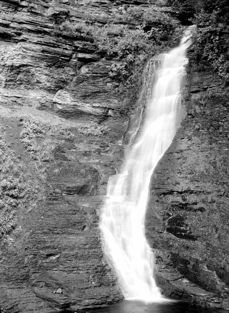 A black and white photo of a waterfall snaking down a rocky cliff